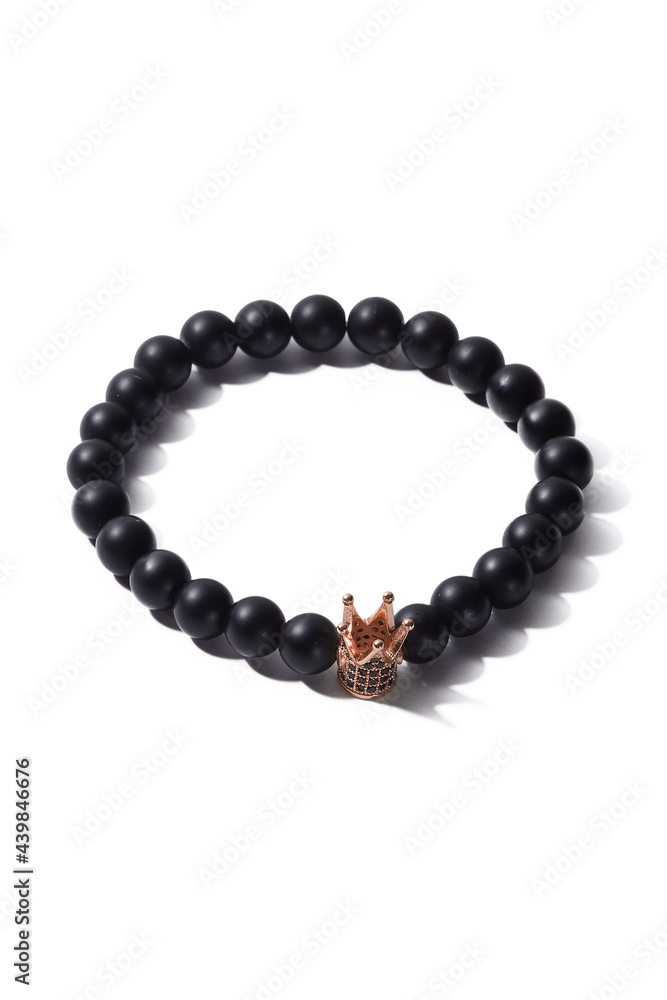 Detail shot of beaded bracelet made of black ornamental stone and decorated with little crown with crystals. Stylish bracelet is isolated on the white background. Detail shot of beaded bracelet made of black ornamental stone and decorated with little crown with crystals. Stylish bracelet is isolated on the white background.