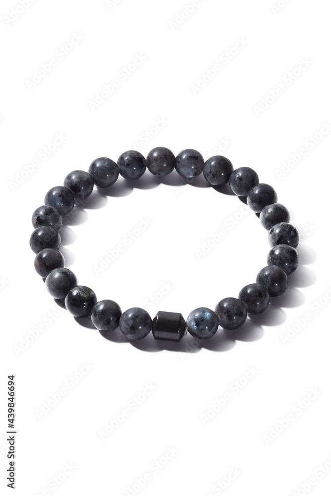 Detail shot of beaded bracelet made of gray ornamental stone and decorated with black hematite cylinder. Stylish bracelet is isolated on the white background. Detail shot of beaded bracelet made of gray ornamental stone and decorated with black hematite cylinder. Stylish bracelet is isolated on the white background.