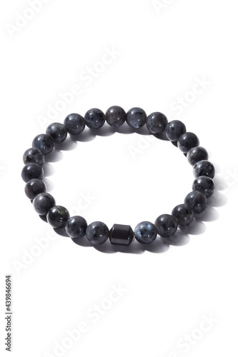 Detail shot of beaded bracelet made of gray ornamental stone and decorated with black hematite cylinder. Stylish bracelet is isolated on the white background. 