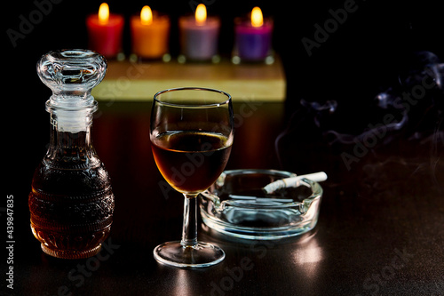 glass of alcohol and bottle with cigarette isolate on black 