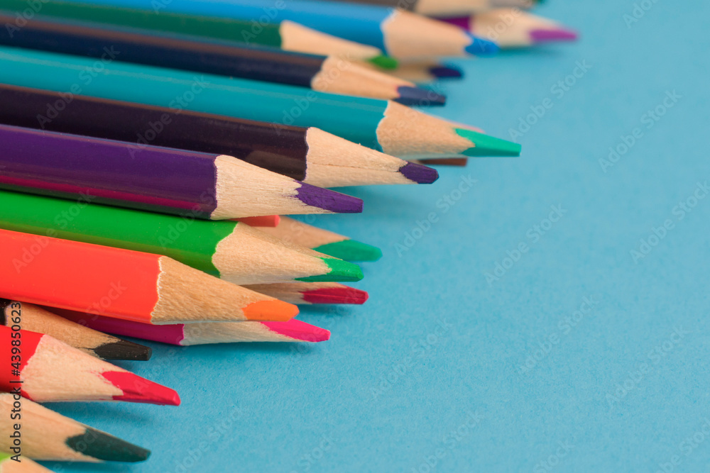 Obraz premium Close-Up Of colored pencils placed on blue paper background with copy space for your image or text. High quality photo