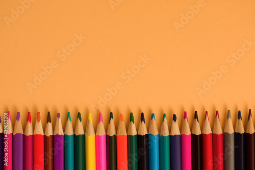 Close-Up Of colored pencil placed on yellow paper background with copy space for your image or text. High quality photo