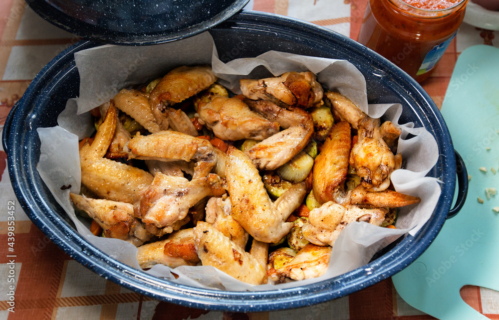 Oven roasted chicken wings with vegetables on a baking tray. Just now ready homemade food. Top view.