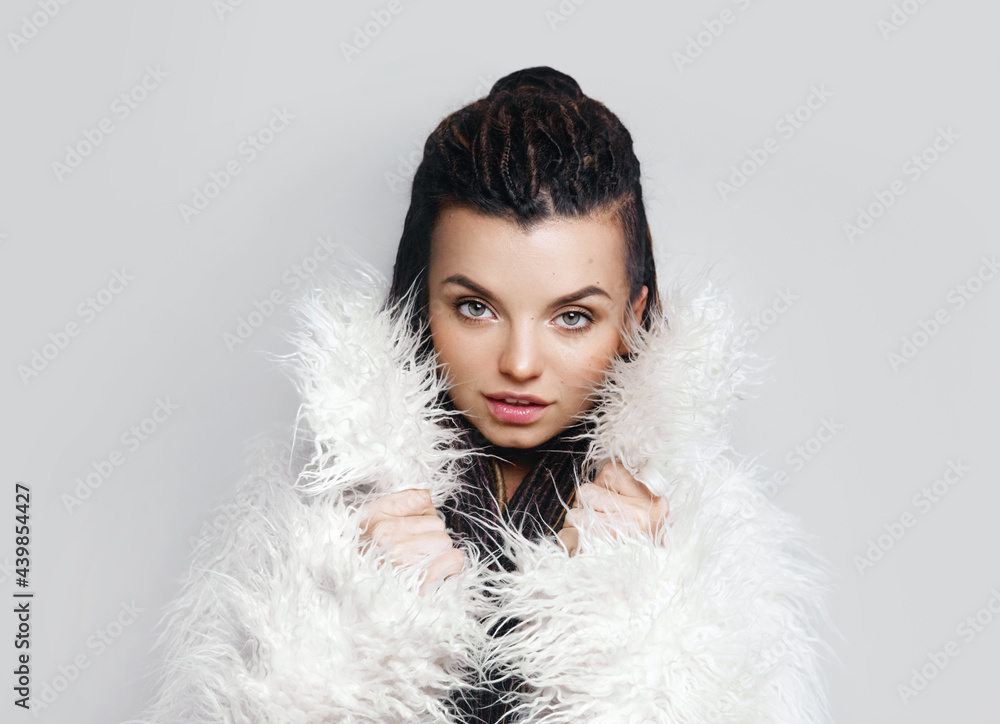 Portrait of a beautiful girl with dreadlocks. Fashionable fur coat. Beauty.