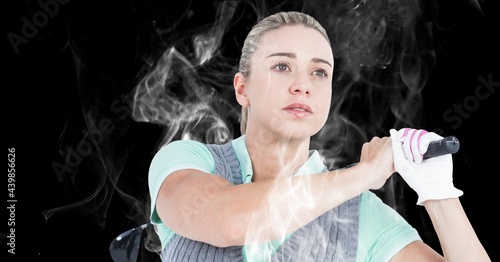 Close up of caucasian female golf player swinging golf club against smoke effect on black background
