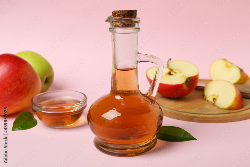 Homemade apple vinegar and ingredients on pink background Homemade apple vinegar and ingredients on pink background