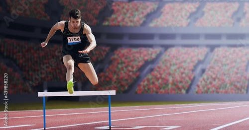 Papier peint Caucasian male athlete jumping over a hurdle against sports stadium in backgroun