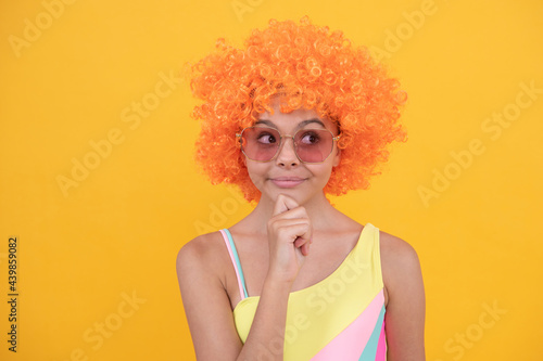 cheerful thinking teen girl in sunglasses on yellow background, emotions.