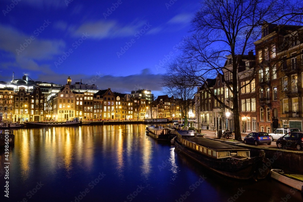 city ​​at night lights in buildings that reflect illumination on the European river containing trees and boats and on the street cars and people