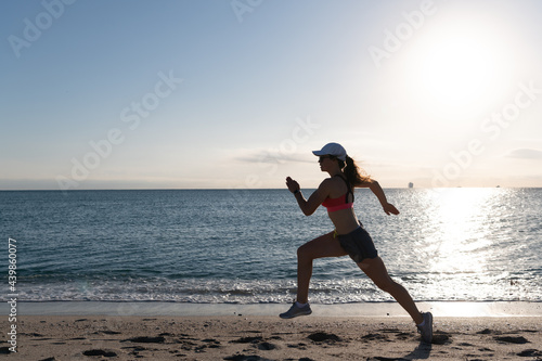 Energetic running woman in activewear run on beach sand along seaside, runner