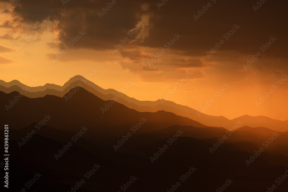 Obraz premium Mountains shape at sunset sky. Relaxing mountain landscape with colorful sunset, nature outdoor travel background.