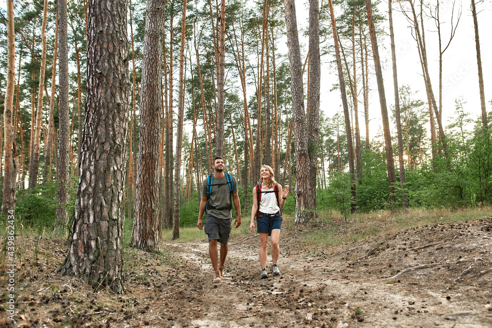 Happy young caucasian couple trekking in summer wood