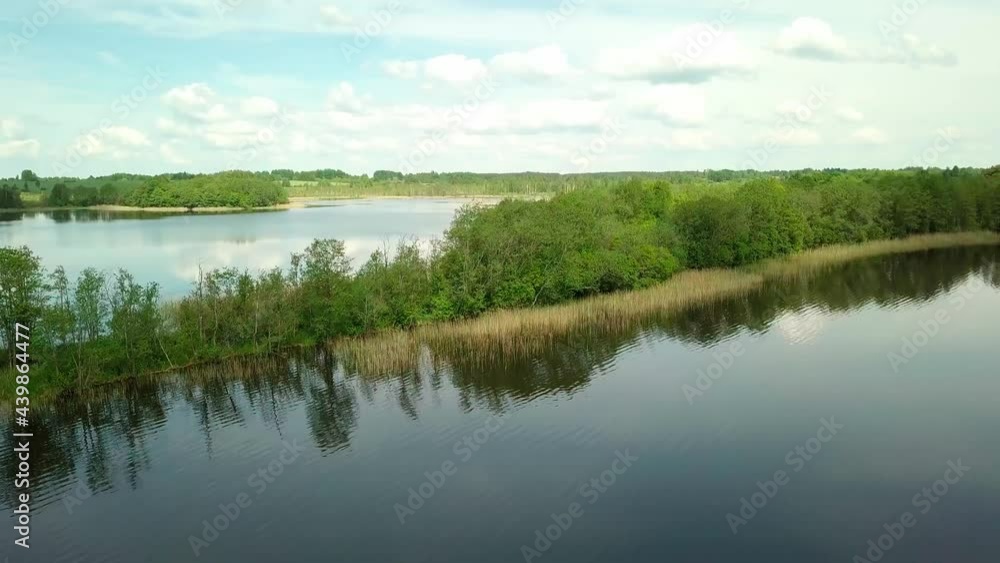 Flying over a taiga forest lake. The drone flies over a picturesque place, a large lake and a small island surrounded by forest and greenery in spring on a sunny summer day. Belarus, Braslav Lakes. Flying over a taiga forest lake. The drone flies over a picturesque place, a large lake and a small island surrounded by forest and greenery in spring on a sunny summer day. Belarus, Braslav Lakes.