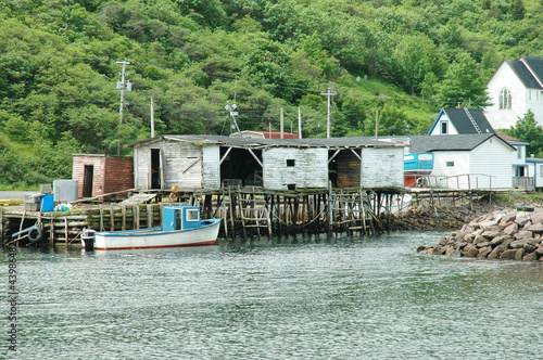 Weathered fishing shack with storage containers and a docked fishing boat