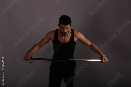The fighter with two vintage swords on gray background