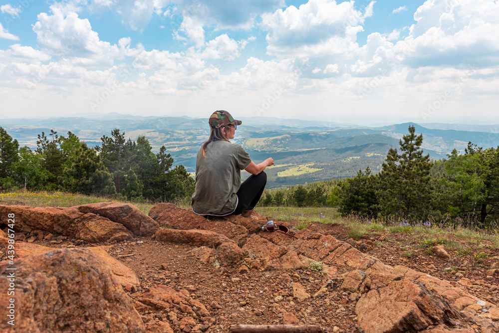 Tourist girl hiker, photographer resting at the top of the mountain and enjoying amazing landscape view of mountains and beautiful sky Tourist girl hiker, photographer resting at the top of the mountain and enjoying amazing landscape view of mountains and beautiful sky