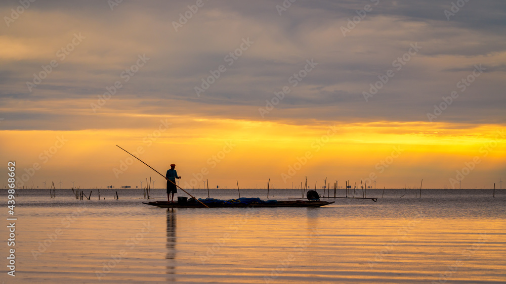Asian fisherman on wooden boat for catching fish in lake in morning