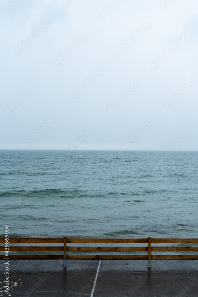 Wet wood railing in front of the sea on a cloudy windy day Wet wood railing in front of the sea on a cloudy windy day