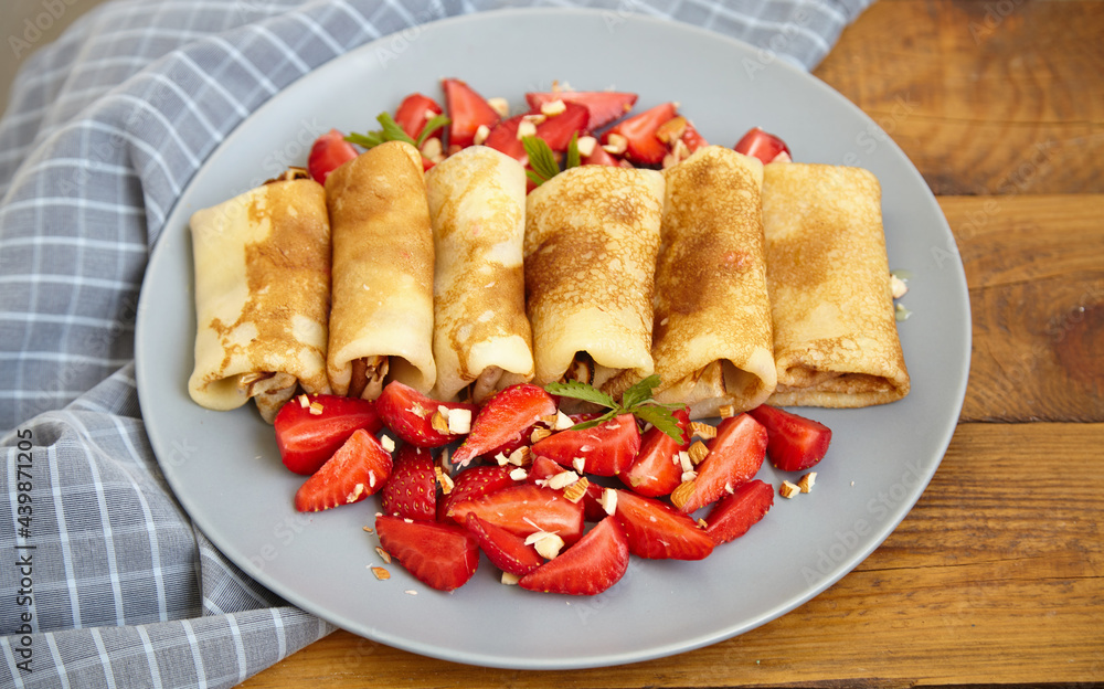 Pancakes, thin pancakes with fresh strawberries. On a wooden background. Copy space. Pancakes, thin pancakes with fresh strawberries. On a wooden background. Copy space.