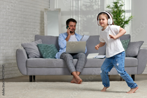 kid dancing and busy dad working with laptop at home