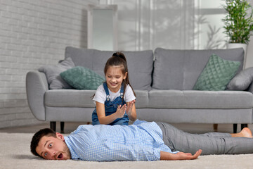 happy little child daughter doing massage to father