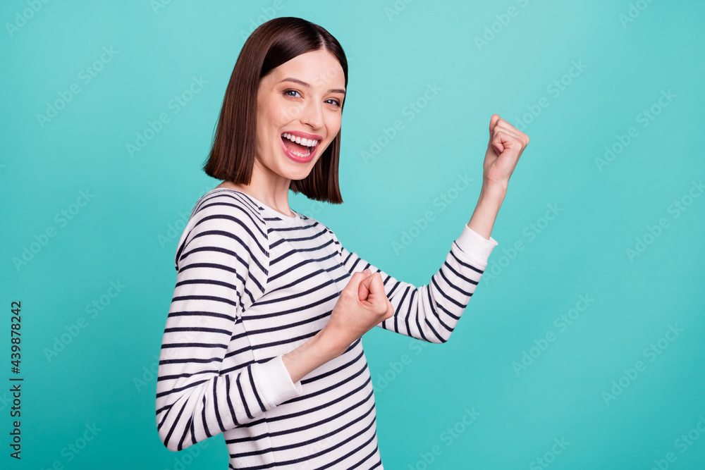 Photo of cheerful astonished lady celebrate victory wear striped shirt isolated on turquoise color background Photo of cheerful astonished lady celebrate victory wear striped shirt isolated on turquoise color background