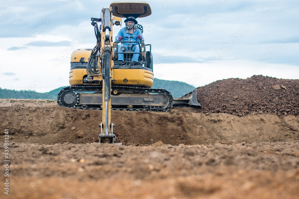 Obraz premium mini excavator digging soil with mountain background