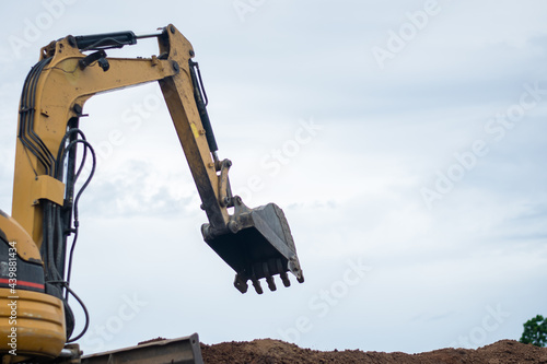 A mini excavator is digging the soil in the field.