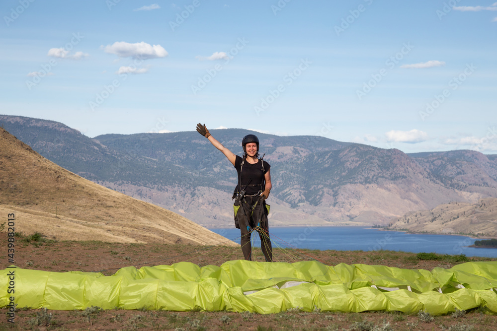 Adventurous Caucasian Woman learning to Fly on a Paraglider around the mountains. Savona, British Columbia, Canada