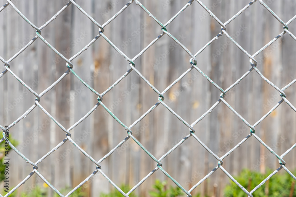Texture of Rhombic cells of a white metal lattice is in the sunny day in the summer park on the gray wood background Texture of Rhombic cells of a white metal lattice is in the sunny day in the summer park on the gray wood background