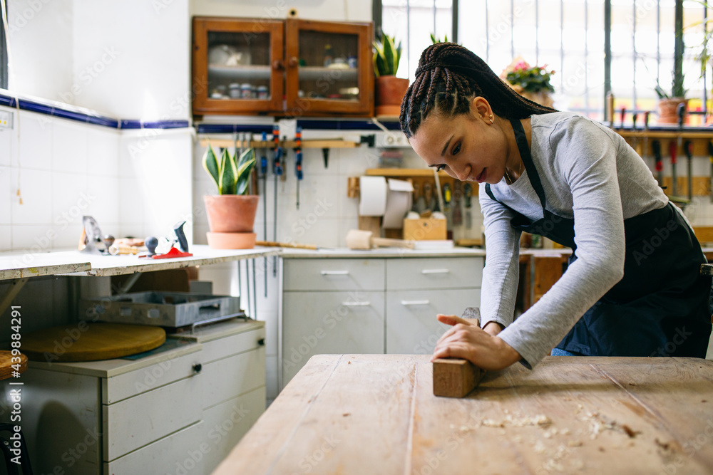 Female carpenter working with plane in workshop Female carpenter working with plane in workshop
