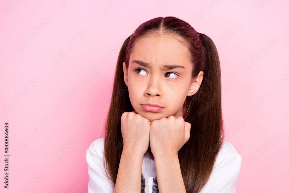 Photo of unhappy upset little small girl look empty space hold face fists isolated on pastel pink color background Photo of unhappy upset little small girl look empty space hold face fists isolated on pastel pink color background