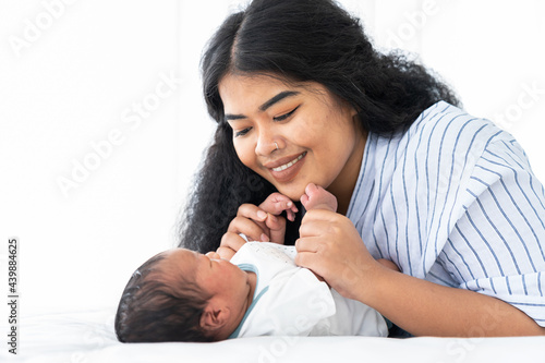 Newborn baby and young mother. Smiling mom with African American newborn on bed. family, love, happy and new life concept