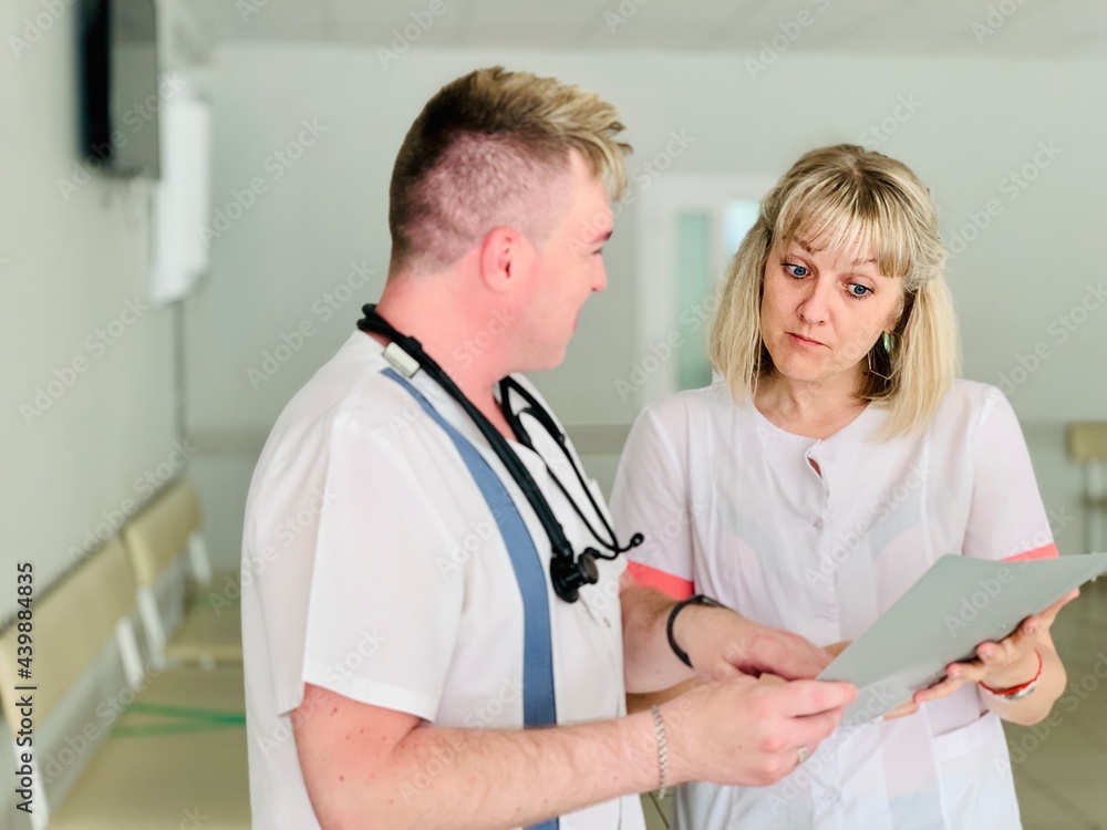 Fototapeta premium Two doctors a man and a woman are examining medical documents.