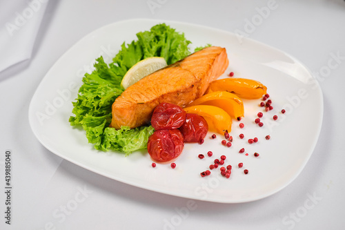 Fried salmon steak with potatoes and vegetables on wooden table