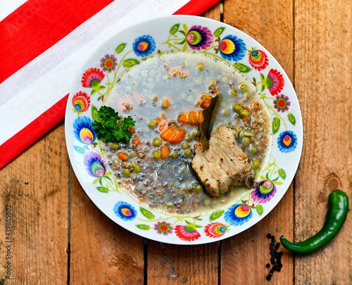 Green soup with buckwheat, carrot, chilli papper pork meat and green bean in white plate on wooden background.. photo