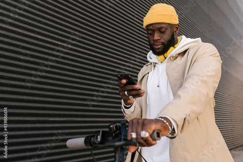 Man using a mobile standing on an electronic scooter. photo