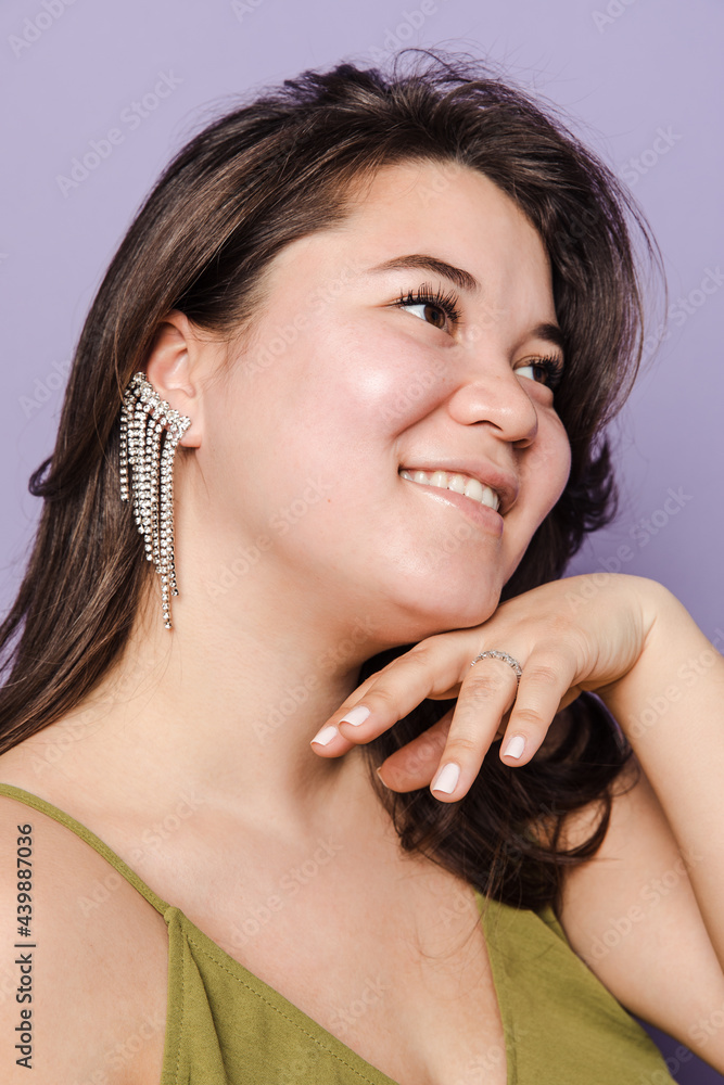 Portrait of a woman in green dress with an ear cuff smiling Portrait of a woman in green dress with an ear cuff smiling