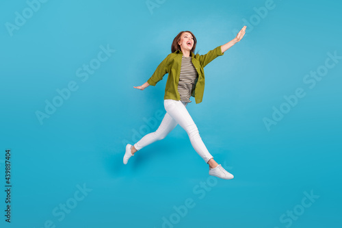 Full length photo of happy young woman jump up air good mood walk isolated on blue color background