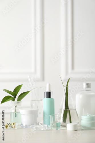 Natural ingredients for cosmetic products and laboratory glassware on white table