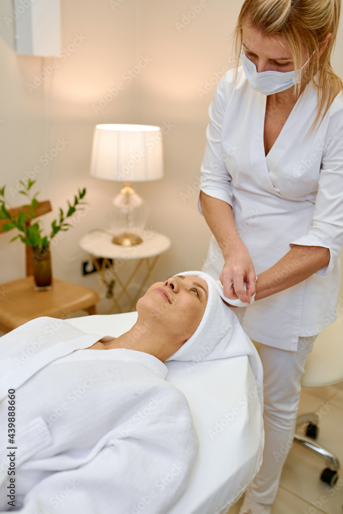 Cosmetologist doing face massage adult woman patient in beauty salon Cosmetologist doing face massage adult woman patient in beauty salon