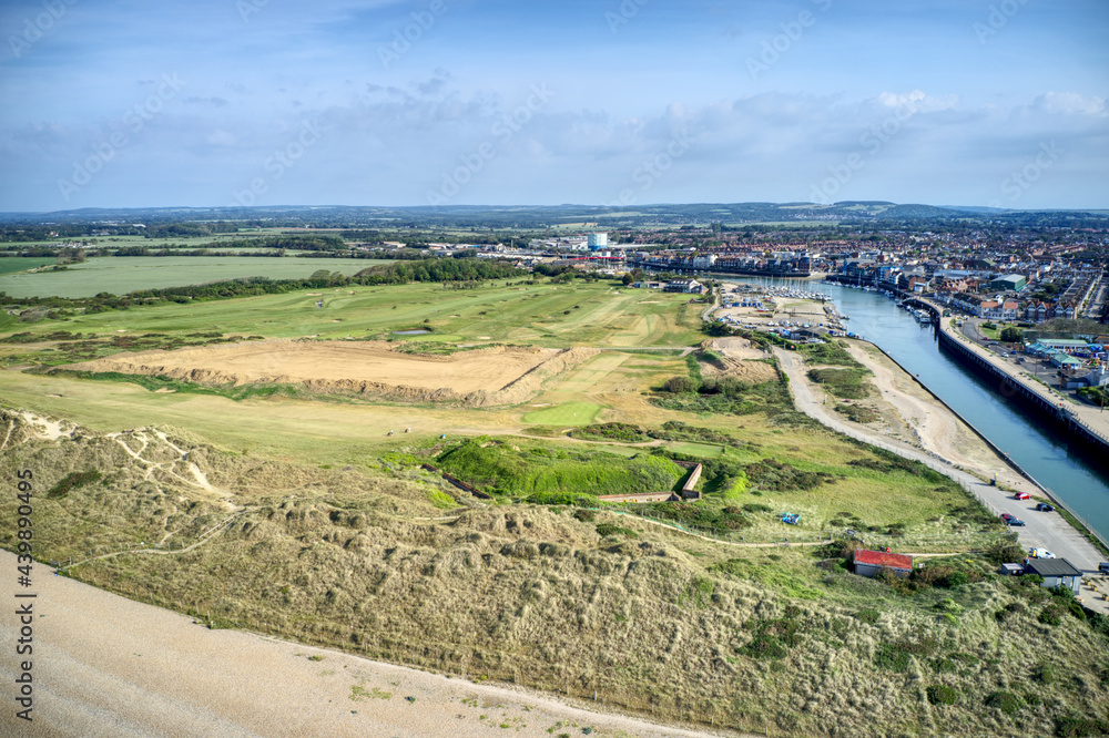 The dunes on West Beach protecting the golf course and revealing the River Arun running past the town of Littlehampton. Aerial photo.