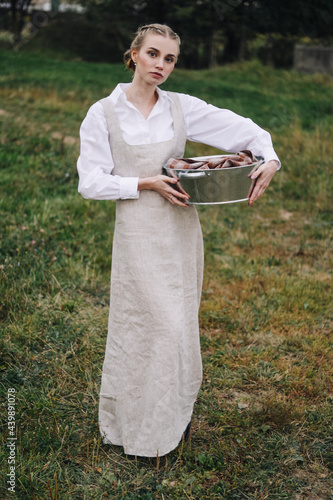 beautiful young woman in a light dress with a basin in her hands. Agriculture.