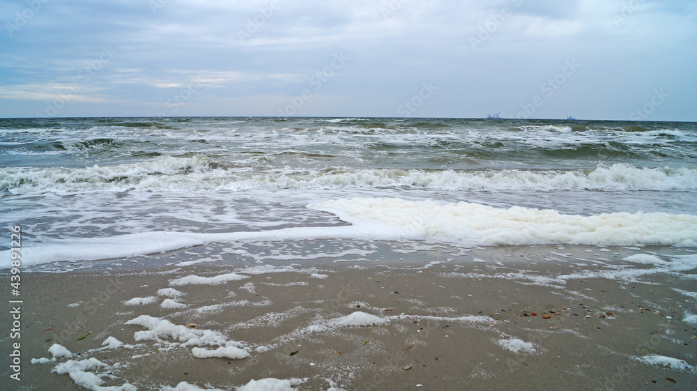 Black sea with waves and white foam under the blue sky in the clouds on a spring cloudy day Black sea with waves and white foam under the blue sky in the clouds on a spring cloudy day