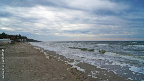 Black sea with waves and white foam under the blue sky in the clouds on a spring cloudy day