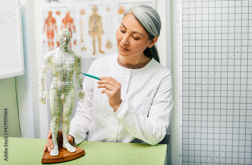 Fotografie Mature woman acupuncturist, doctor of traditional Chinese medicine showing point
