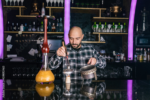 Man preparing hookah at night club photo