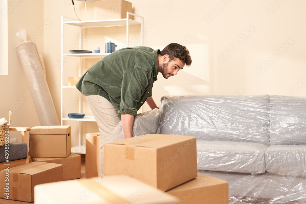 Young male moving couch to wall Young male moving couch to wall