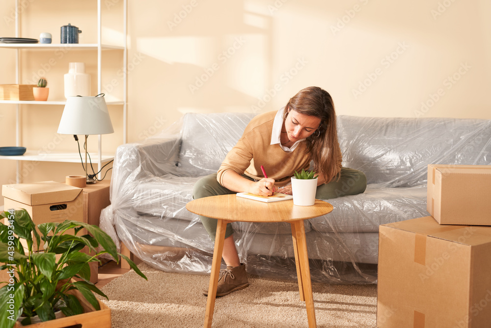 Young female writing in notepad during relocation Young female writing in notepad during relocation