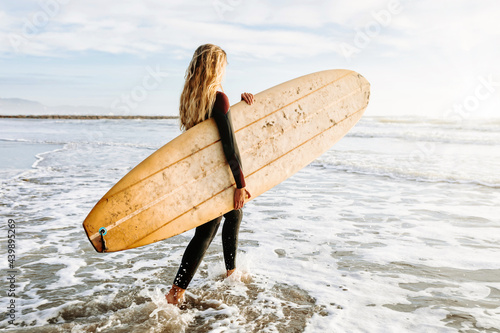 Female surfer walking at the beach with surfboard photo